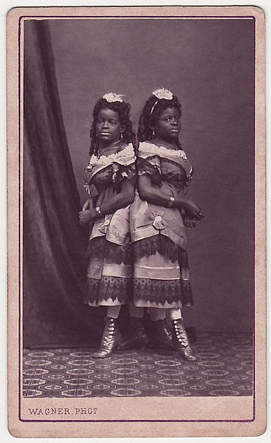 Millie and Christine McCoy (1851-1912) were conjoined twins born into slavery. They and their mother were sold to a showman, Joseph Smith. Smith and his wife educated the girls; they eventually could speak five languages, dance, play music, and sing. They were known as 'The Two Headed Nightingale'. In the 1880s they retired and purchased a small farm. Millie died of tuberculosis at age 61, with Christine following hours later. They remain one of the oldest-lived set of conjoined twins. From https://www.flickr.com/photos/29482804@N06/2758581106/in/set-72157616379342621